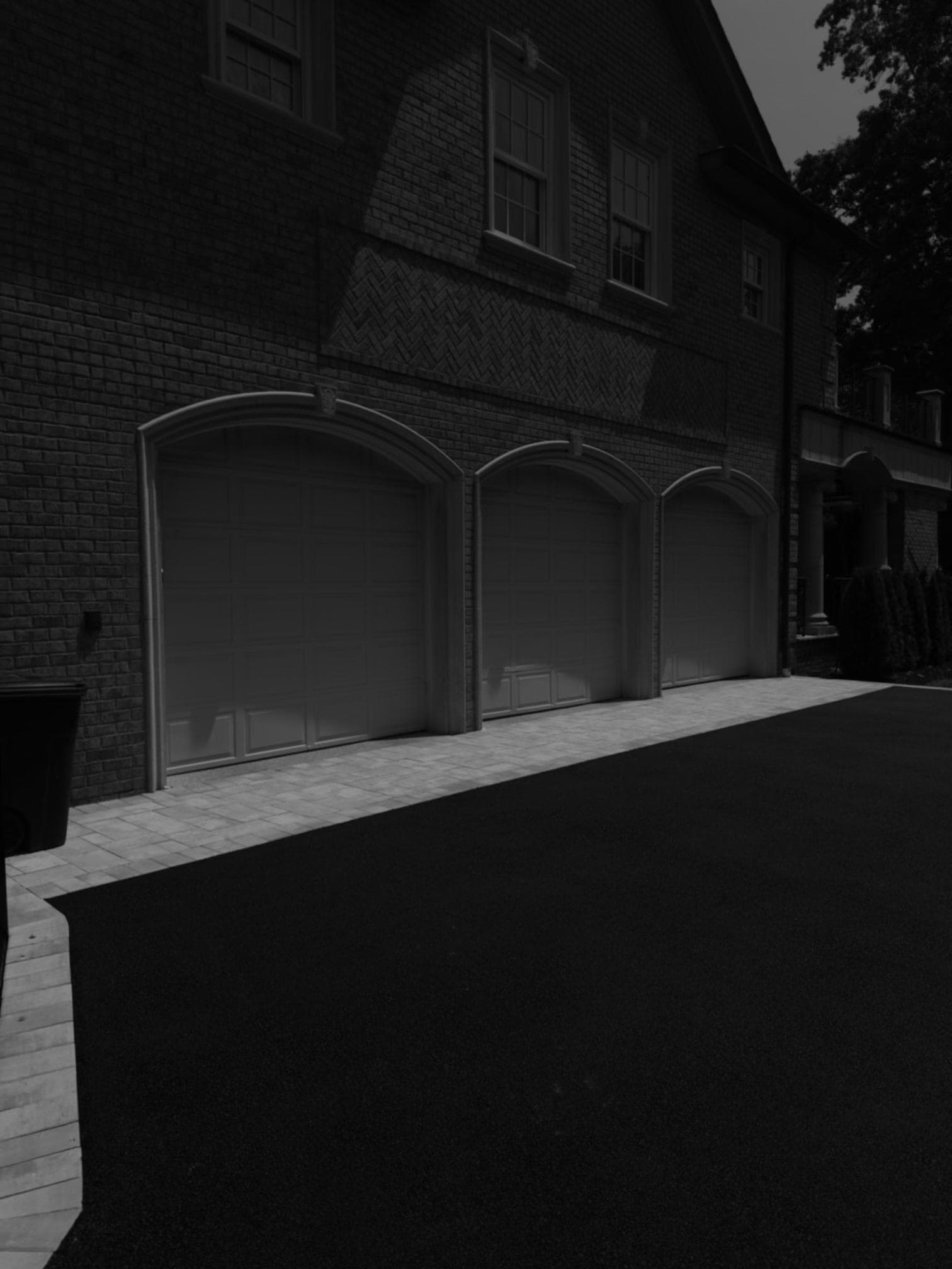 Three-car garage with paver apron and asphalt driveway at Lloyd Harbor estate