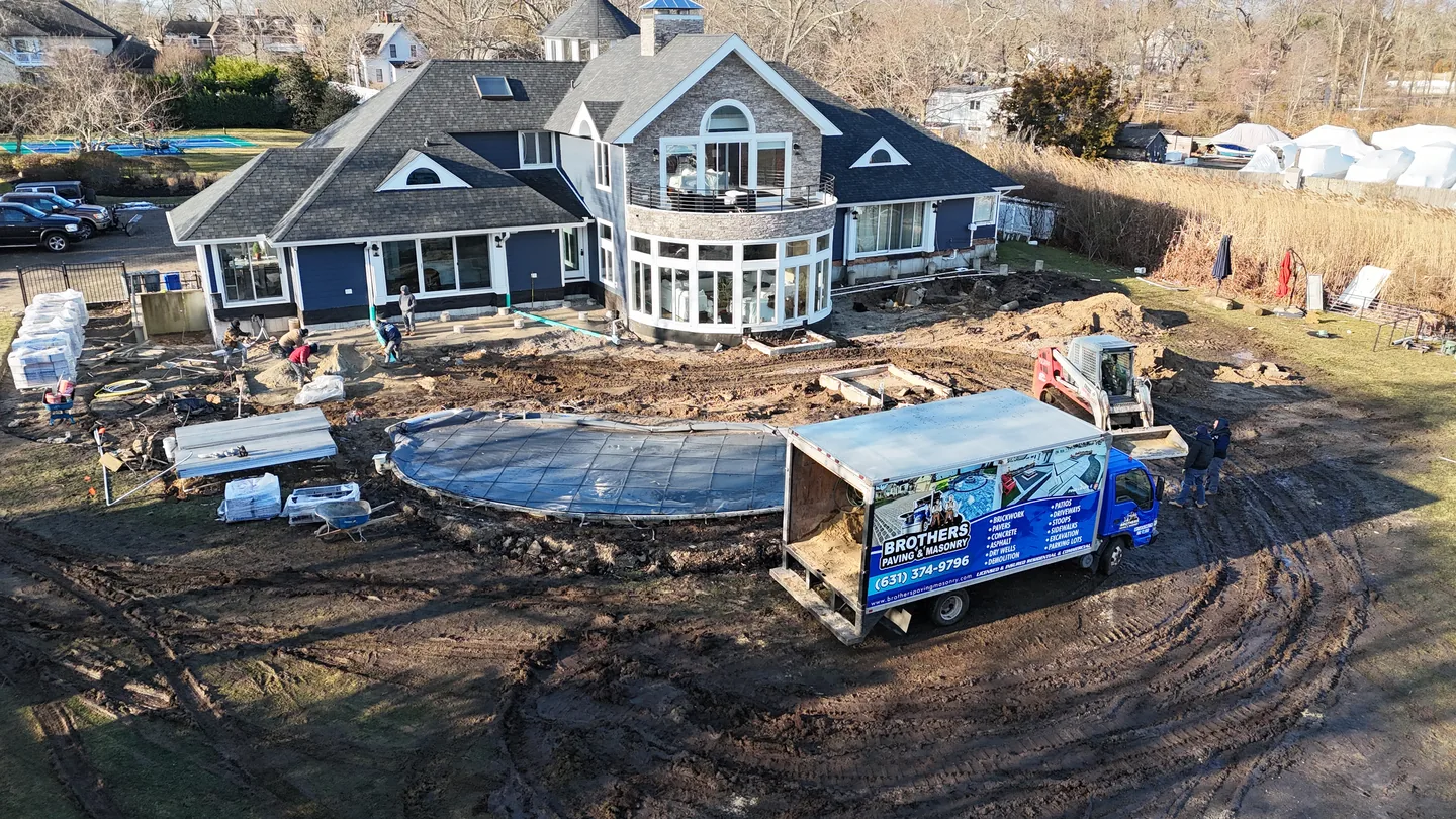 Brothers Paving & Masonry box truck on the frozen Great River site beside the pool shell during winter construction