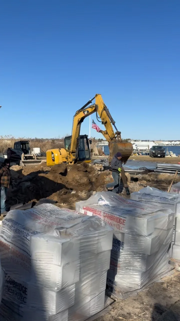 Excavator working the frozen rear yard during winter site work, Great River