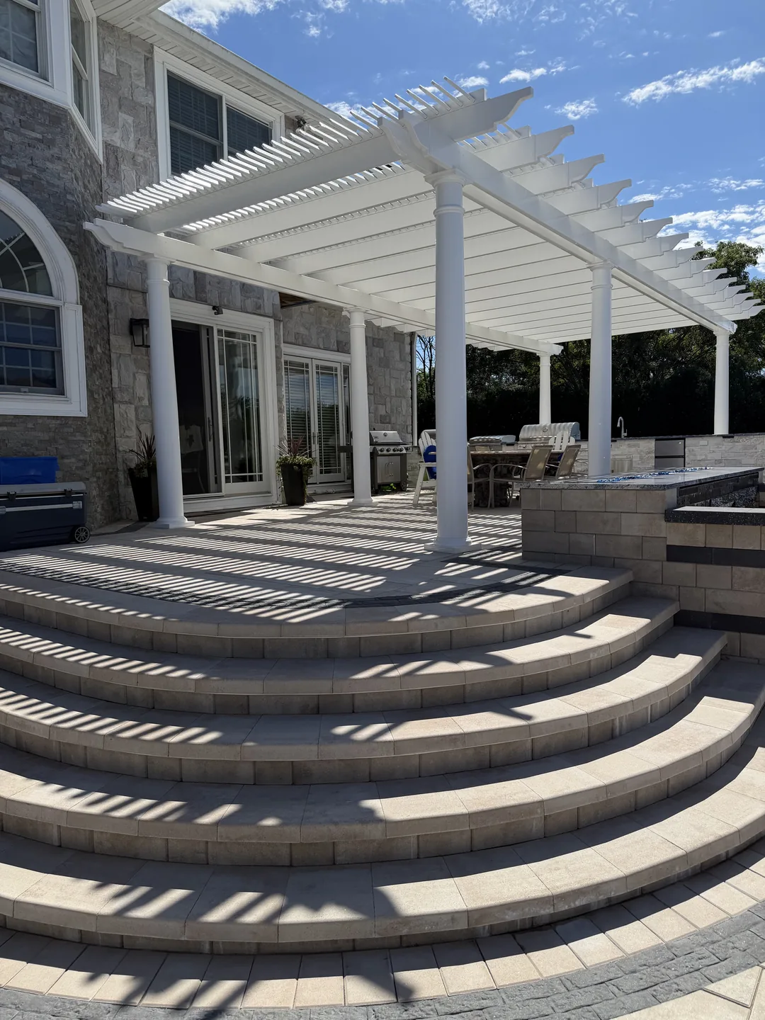 Pergola shadows across the paver deck toward the house, East Northport