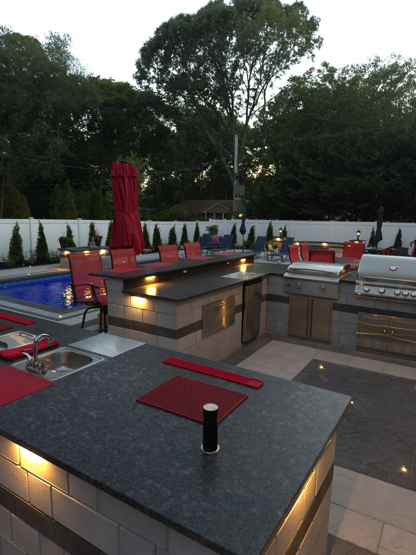 Outdoor kitchen and bar run lit at dusk, Nesconset