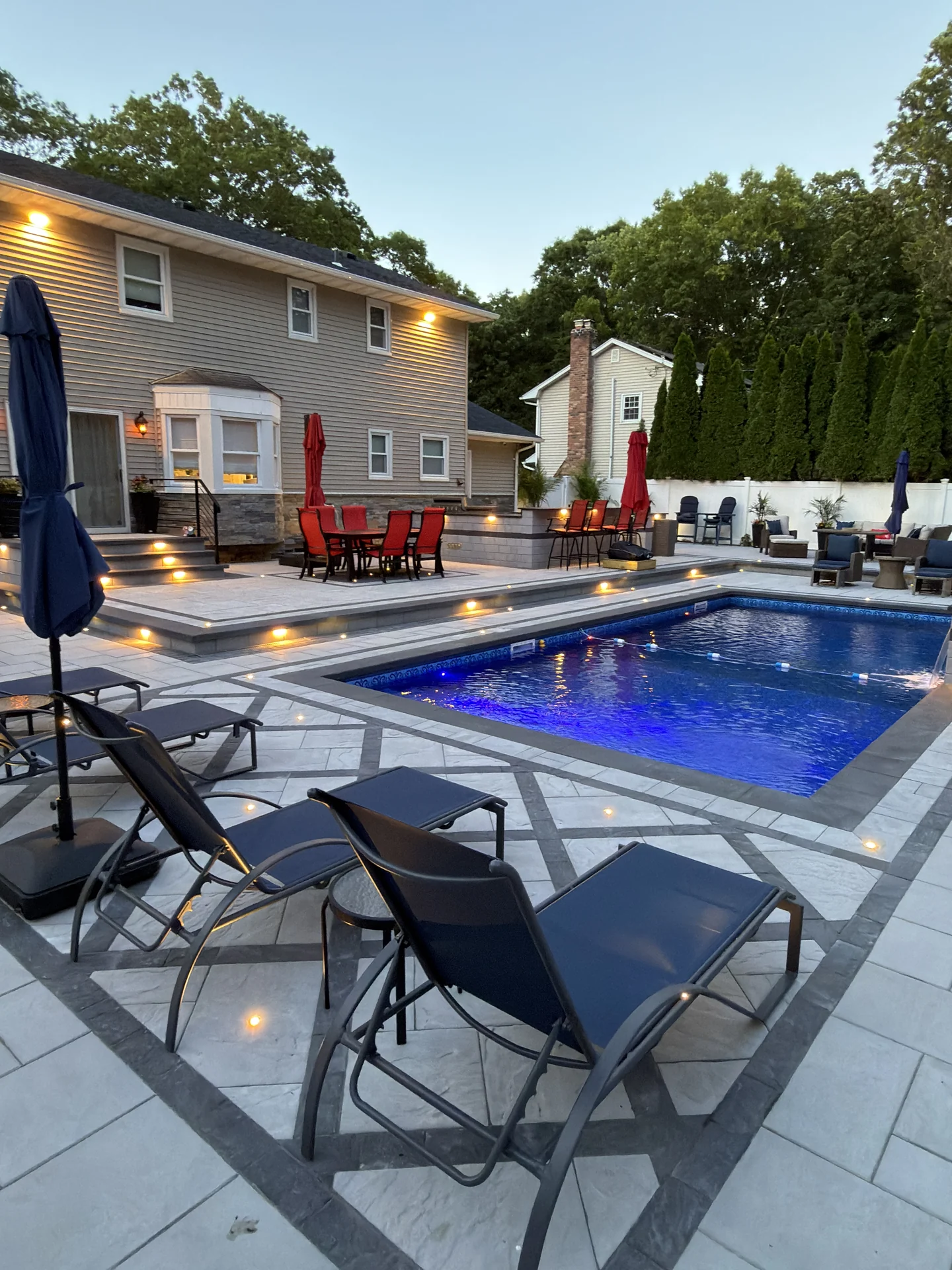 Loungers along the pool with the deck lighting on at dusk, Nesconset