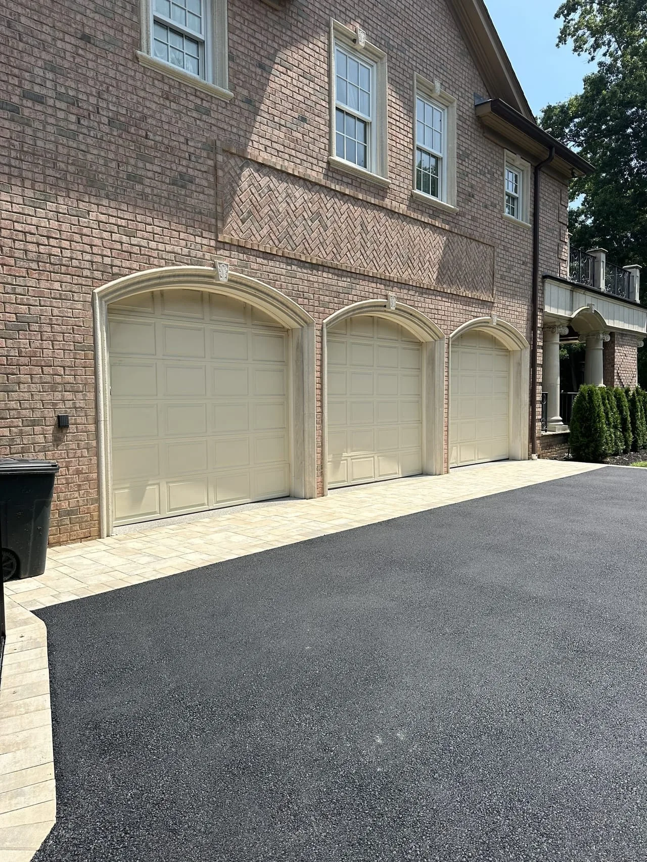 Three-car garage with paver apron and asphalt driveway at Lloyd Harbor estate