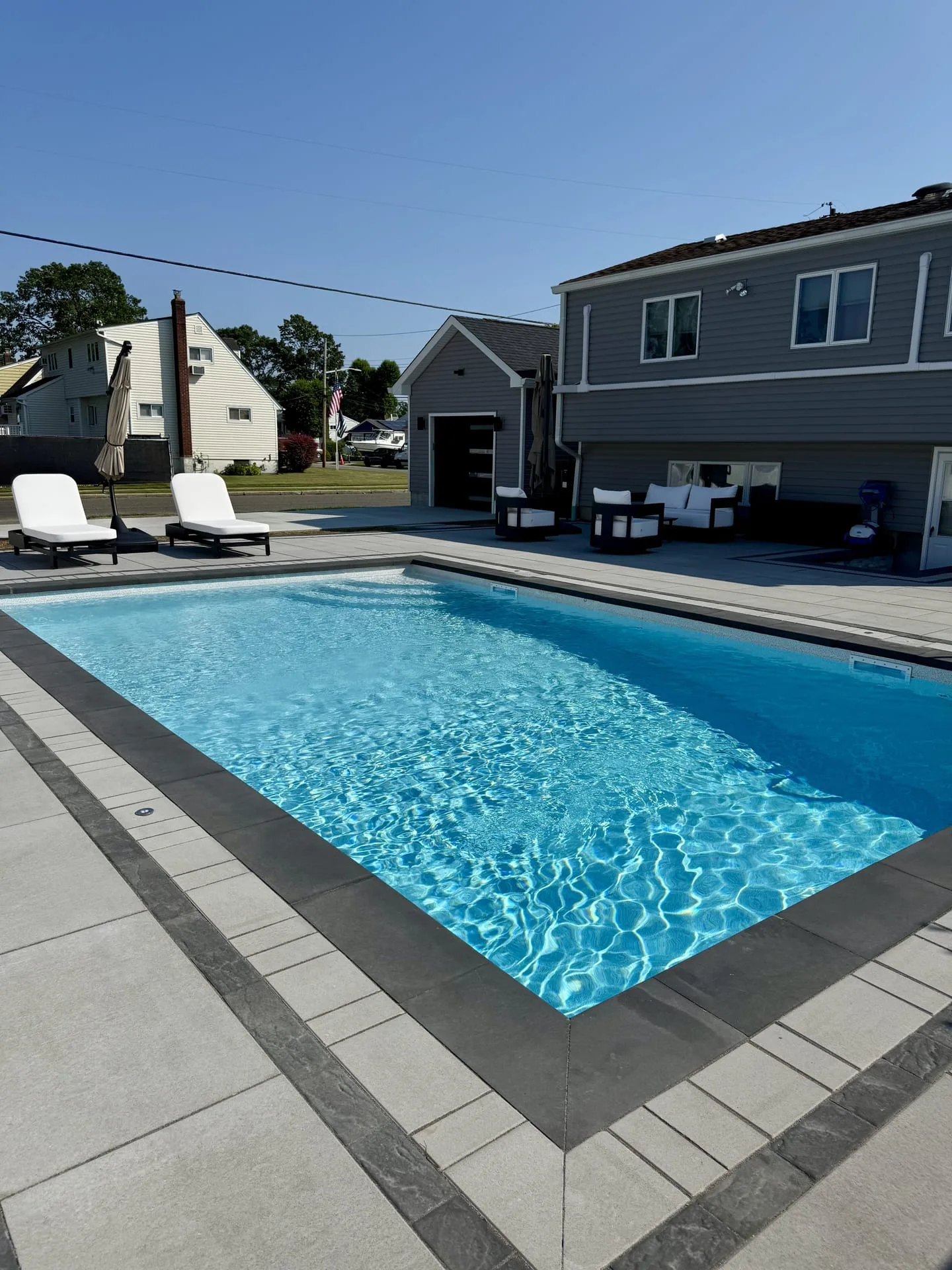 Resort-style paver pool deck with lounge area in Cold Spring Harbor