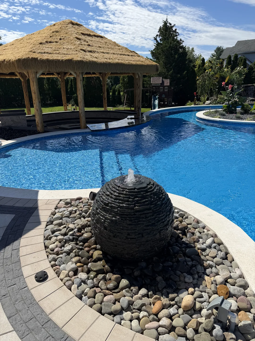 Sculptural sphere water feature on a river-rock bed, East Northport