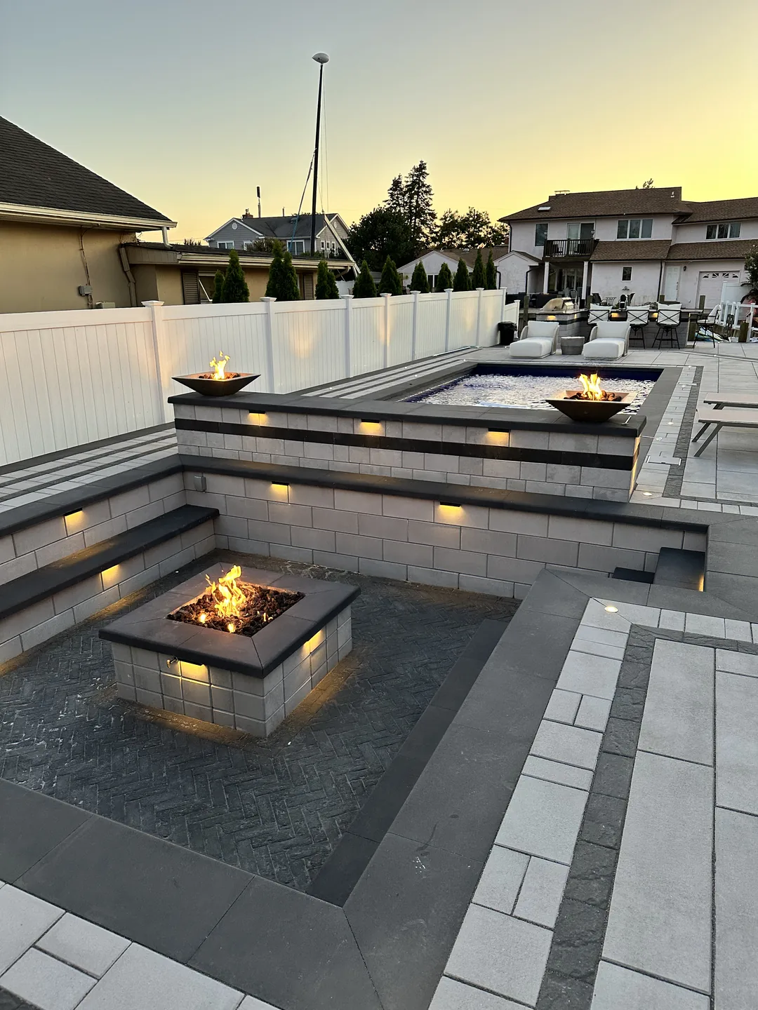 Twin fire bowls flanking the raised spa at dusk, Massapequa