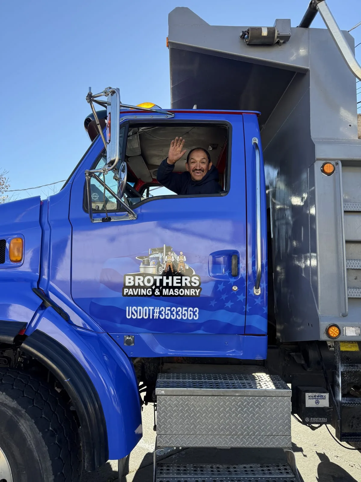 Crew member waving from branded Brothers Paving truck